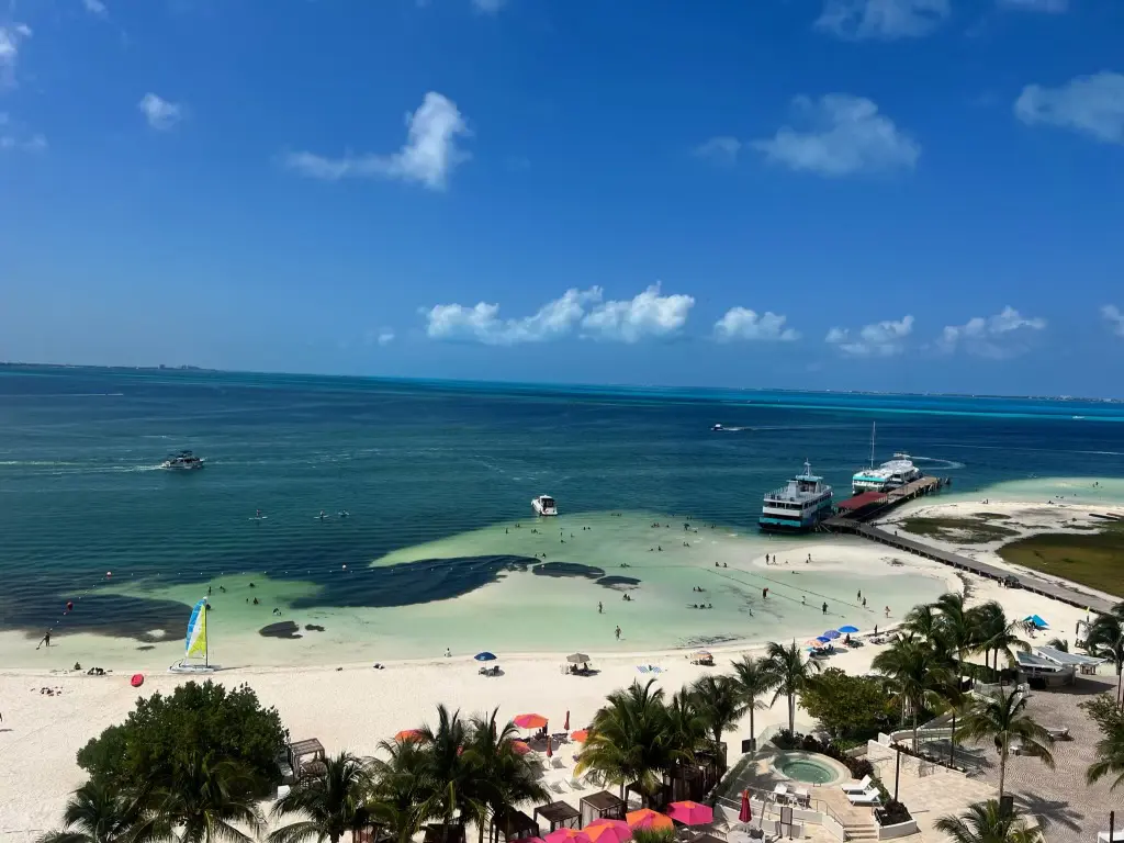 A beach with people swimming and boats in the water.