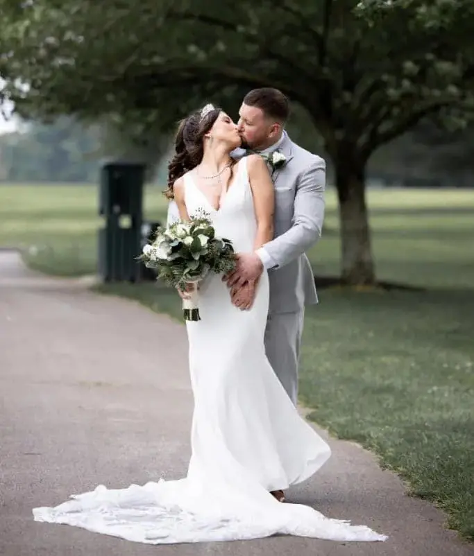 A bride and groom kissing on the side of a road.